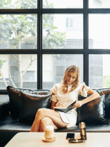 woman sitting on couch creating a plan in her notebook