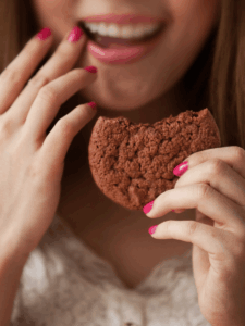 Woman with cookie wiping the corner of her mouth